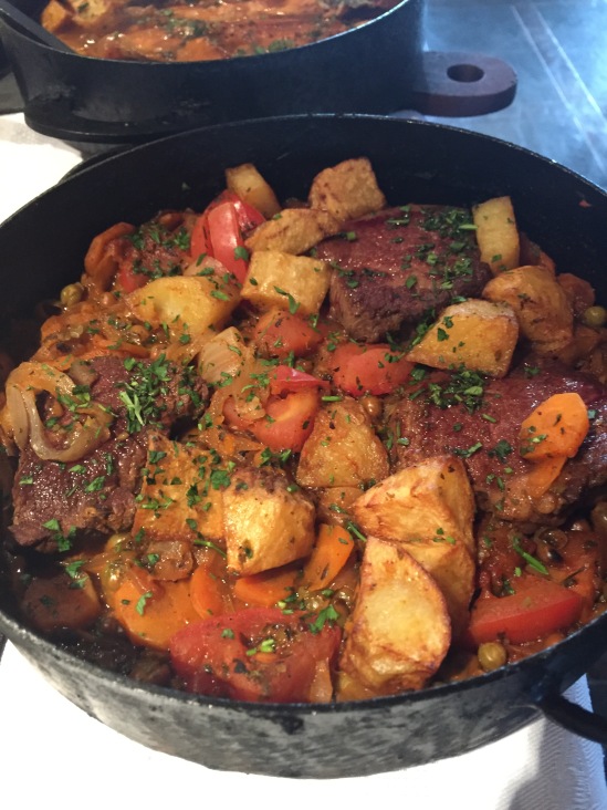 Cast iron pot full of pan seared sirloin, roasted vegetables, and some kind of amazing tomato sauce.